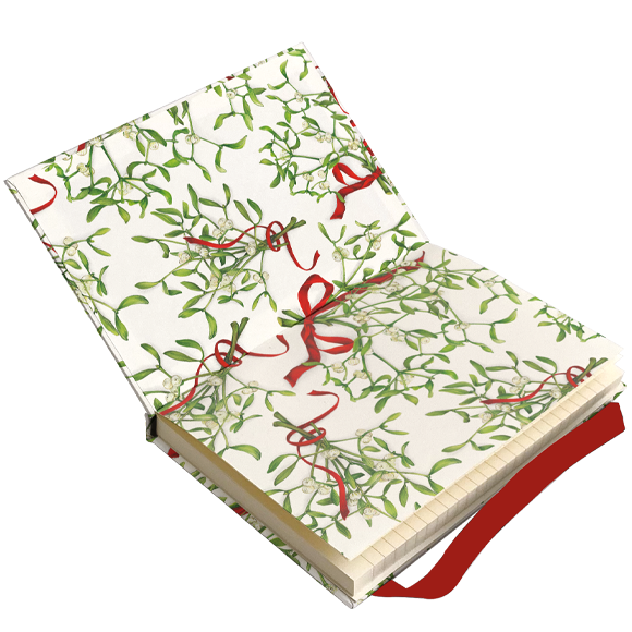 A hardcover notebook with a festive holiday design, featuring a cream-colored cover patterned with green mistletoe branches and red ribbon bows, shown open on a plain white background.