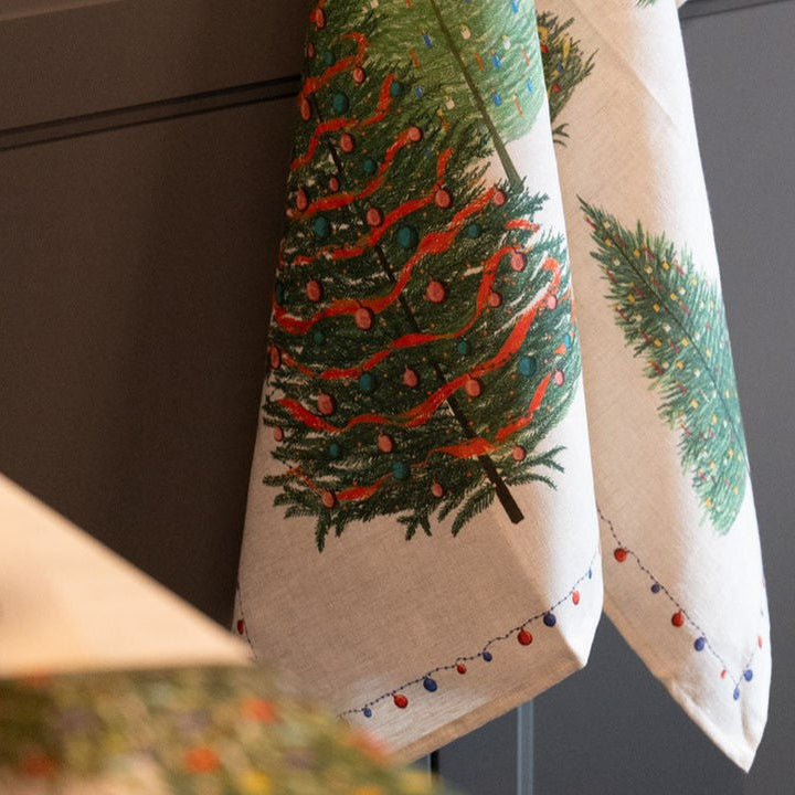Decorative towel with Christmas tree design hanging on a cabinet.