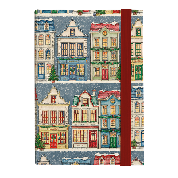A hardcover notebook featuring a festive Christmas village pattern with colorful houses on a snowy blue-gray background, bound with a vertical dark red elastic closure band.