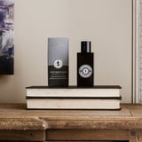 'Gentlemen's Club' Patchouli & Sandalwood Eau De Toilette - Gift for men - A grey bottle with a grey and brown gift box. Lifestyle image of the perfume stood on two books.